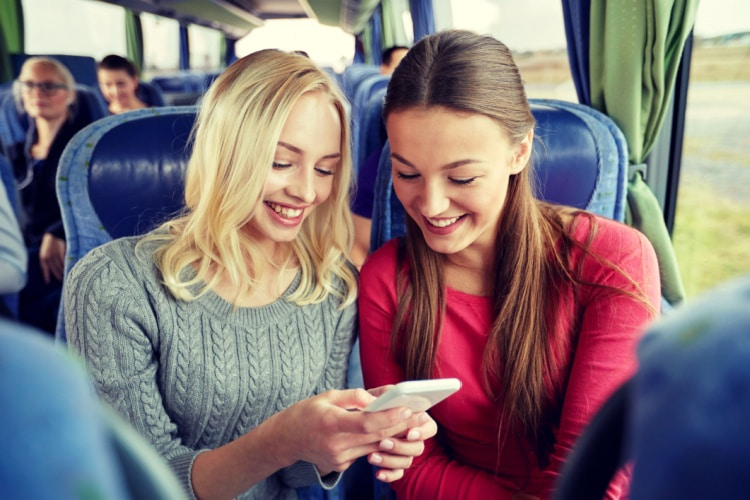 two students chat on a charter bus